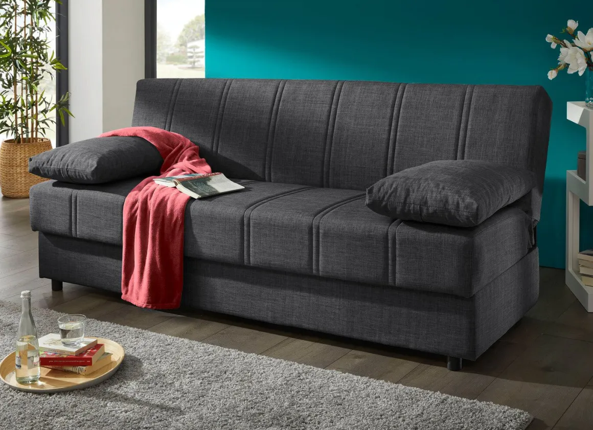 Frei im Raum aufstellbares Schlafsofa mit Dekokissen und Bettkasten